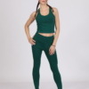 Women with brown hair is wearing dark green organic cotton tank top and dark green organic cotton leggings