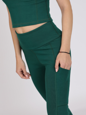 Women with brown hair is wearing dark green organic cotton tank top and dark green organic cotton leggings