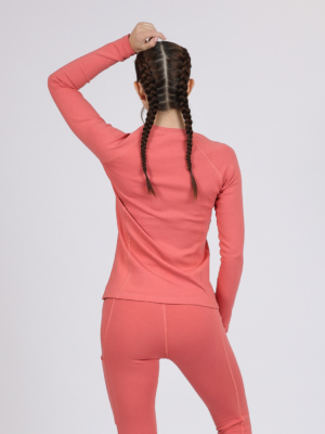 Women with brown hair is wearing pink organic cotton long sleeve top and pink organic cotton leggings