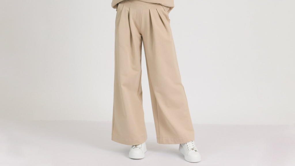 Woman with blond hair wearing beige organic cotton blouse and beige long wide pants
