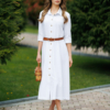 Woman wearing white organic cotton shirt dress with bracelet sleeves coconut buttons and waist belt