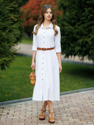 Woman wearing white organic cotton shirt dress with bracelet sleeves coconut buttons and waist belt