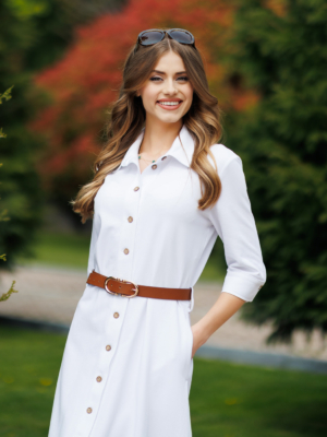 Woman wearing white organic cotton shirt dress with bracelet sleeves coconut buttons and waist belt