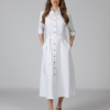 Woman wearing white organic cotton shirt dress with bracelet sleeves coconut buttons and waist belt