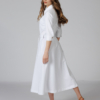 Woman wearing white organic cotton shirt dress with bracelet sleeves coconut buttons and waist belt