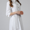 Woman wearing white organic cotton shirt dress with bracelet sleeves coconut buttons and waist belt