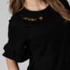 Woman wearing black organic cotton pants and black organic cotton t-shirt with embroidery "Let it bee"