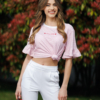 Woman wearing white organic cotton pants and pink striped organic cotton t-shirt with embroidery "Less is more"