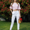 Woman wearing white organic cotton pants and pink striped organic cotton t-shirt with embroidery "Less is more"