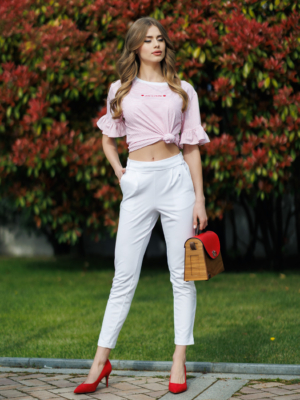 Woman wearing white organic cotton pants and pink striped organic cotton t-shirt with embroidery "Less is more"