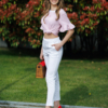 Woman wearing white organic cotton pants and pink striped organic cotton t-shirt with embroidery "Less is more"