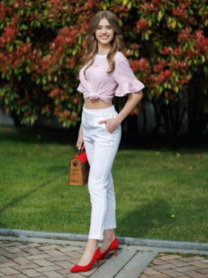 Woman wearing white organic cotton pants and pink striped organic cotton t-shirt with embroidery "Less is more"