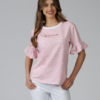 Woman wearing white organic cotton pants and pink striped organic cotton t-shirt with embroidery "Less is more"