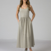 Woman wearing gray organic cotton dress with a flared skirt, midi length, square neckline, high waist and pockets.