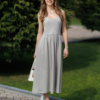 Woman wearing gray organic cotton dress with a flared skirt, midi length, square neckline, high waist and pockets.