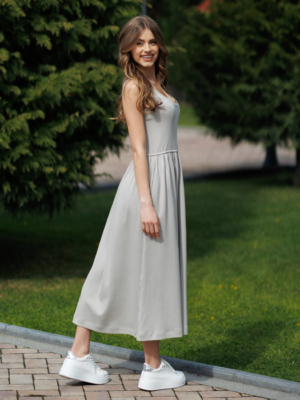 Woman wearing gray organic cotton dress with a flared skirt, midi length, square neckline, high waist and pockets.