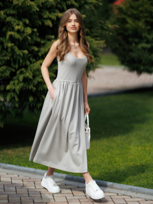 Woman wearing gray organic cotton dress with a flared skirt, midi length, square neckline, high waist and pockets.