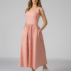 Woman wearing pink organic cotton dress with a flared skirt, midi length, square neckline, high waist and pockets.