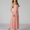 Woman wearing pink organic cotton dress with a flared skirt, midi length, square neckline, high waist and pockets.