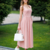Woman wearing pink organic cotton dress with a flared skirt, midi length, square neckline, high waist and pockets.