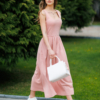 Woman wearing pink organic cotton dress with a flared skirt, midi length, square neckline, high waist and pockets.
