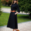 Woman wearing black organic cotton shirt dress with bracelet sleeves coconut buttons and waist belt