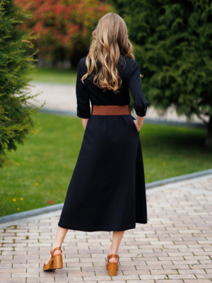 Woman wearing black organic cotton shirt dress with bracelet sleeves coconut buttons and waist belt