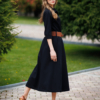Woman wearing black organic cotton shirt dress with bracelet sleeves coconut buttons and waist belt