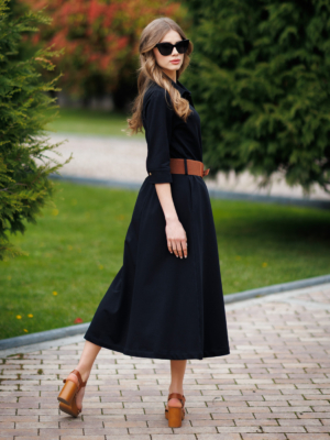Woman wearing black organic cotton shirt dress with bracelet sleeves coconut buttons and waist belt