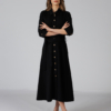 Woman wearing black organic cotton shirt dress with bracelet sleeves coconut buttons and waist belt