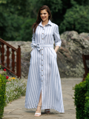 Dark-haired woman wearing a long blue striped linen dress with coconut buttons and collar