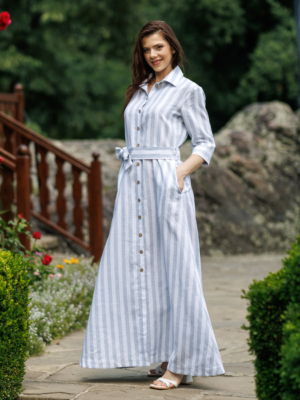 Dark-haired woman wearing a long blue striped linen dress with coconut buttons and collar