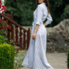 Dark-haired woman wearing a long blue striped linen dress with coconut buttons and collar