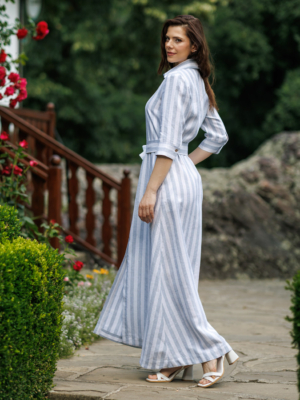 Dark-haired woman wearing a long blue striped linen dress with coconut buttons and collar