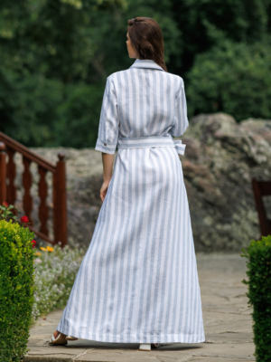Dark-haired woman wearing a long blue striped linen dress with coconut buttons and collar
