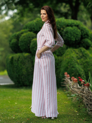 Dark-haired woman wearing a long pink striped linen dress with coconut buttons and collar