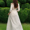 Dark-haired woman wearing a long linen dress with coconut buttons and collar