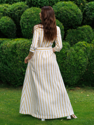 Dark-haired woman wearing a long linen dress with coconut buttons and collar