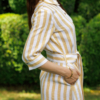 Dark-haired woman wearing a long linen dress with coconut buttons and collar