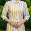 Dark-haired woman wearing a long linen dress with coconut buttons and collar