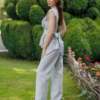 A dark-haired woman wearing an elegant blue melange top, with a belt at the waist, a V-neckline and an open back, and blue melange pants, made of 100% linen.
