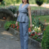A dark-haired woman wearing an elegant blue striped top, with a belt at the waist, a V-neckline and an open back, and dark blue pants made of 100% linen.