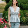 A dark-haired woman wearing an elegant green striped top, with a belt at the waist, a V-neckline and an open back, made of 100% linen.