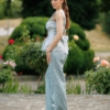 A dark-haired woman wearing an elegant green striped top, with a belt at the waist, a V-neckline and an open back, made of 100% linen.