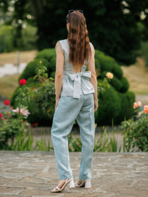 A dark-haired woman wearing an elegant green striped top, with a belt at the waist, a V-neckline and an open back, made of 100% linen.