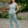 A dark-haired woman wearing an elegant green striped top, with a belt at the waist, a V-neckline and an open back, made of 100% linen.