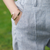 A dark-haired woman wearing an elegant blue melange top, with a belt at the waist, a V-neckline and an open back, and blue melange pants, made of 100% linen.