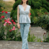 A dark-haired woman wearing an elegant green striped top, with a belt at the waist, a V-neckline and an open back, made of 100% linen.