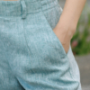 A dark-haired woman wearing an elegant green striped top, with a belt at the waist, a V-neckline and an open back, made of 100% linen.